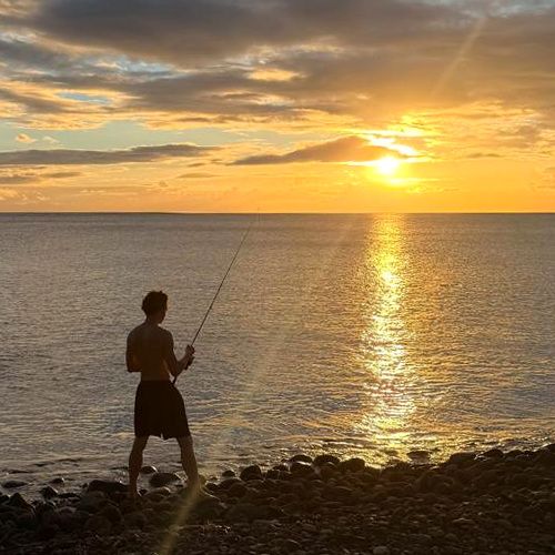Enzo pêche au coucher du soleil, sur une plage de galets